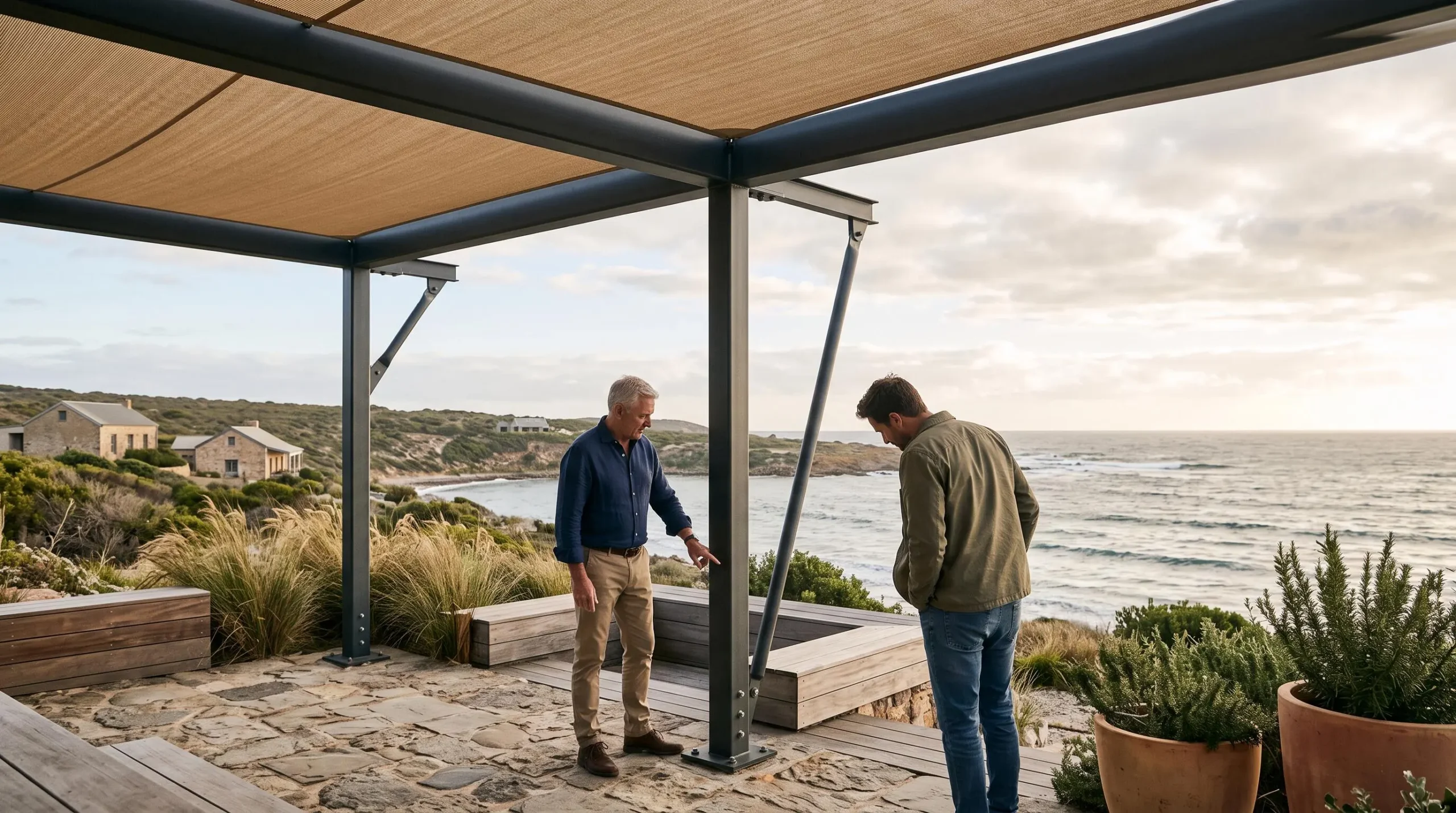 Una estructura de toldo reforzada con soportes laterales en una terraza costera.